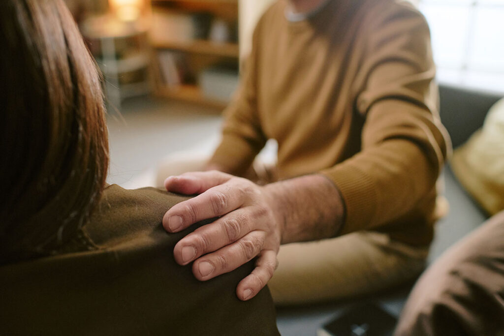 man comforting woman hand on shoulder
